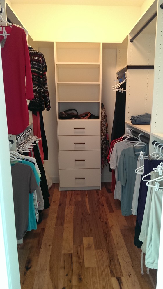 Walk-in closet - mid-sized traditional gender-neutral light wood floor walk-in closet idea in Other with flat-panel cabinets and white cabinets