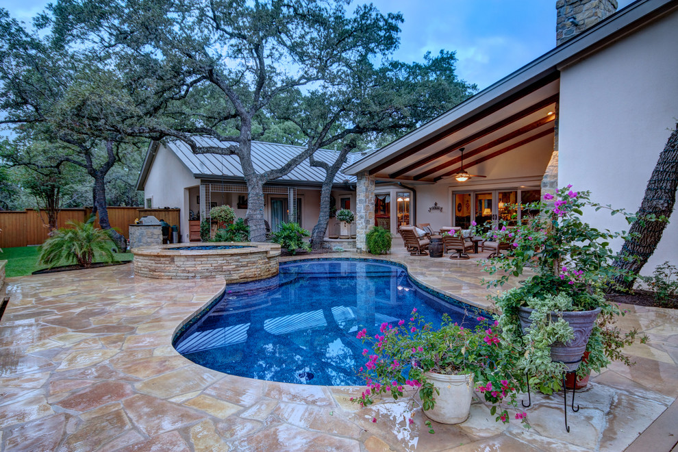 Mid-sized mediterranean backyard kidney-shaped pool in Austin with natural stone pavers and a hot tub.