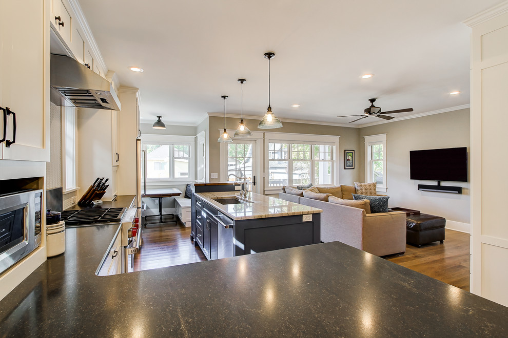 This is an example of a large arts and crafts l-shaped open plan kitchen in Seattle with an undermount sink, shaker cabinets, white cabinets, solid surface benchtops, white splashback, ceramic splashback, stainless steel appliances, medium hardwood floors and with island.