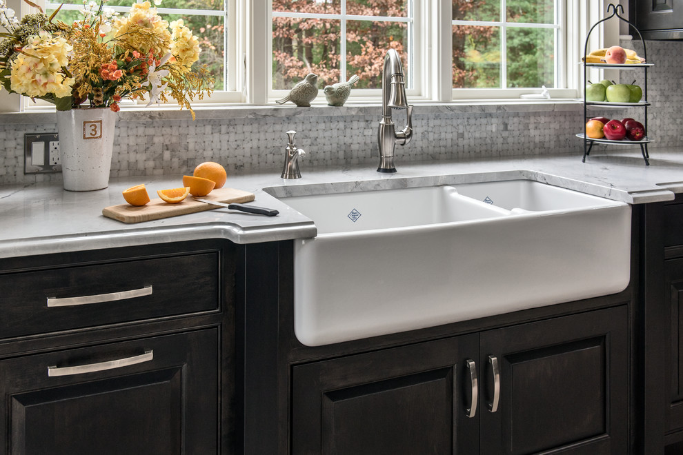 Inspiration for an expansive transitional l-shaped eat-in kitchen in Boston with a farmhouse sink, beaded inset cabinets, black cabinets, quartzite benchtops, grey splashback, stone tile splashback, stainless steel appliances, porcelain floors, with island, grey floor, grey benchtop and vaulted.