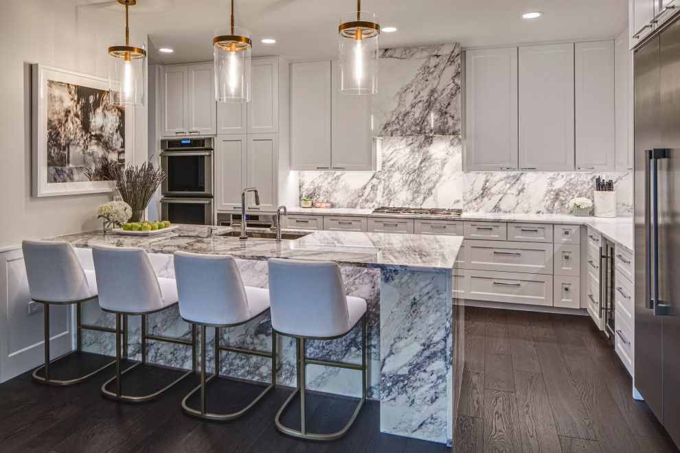Open concept kitchen - large transitional l-shaped dark wood floor and brown floor open concept kitchen idea in Chicago with an undermount sink, shaker cabinets, white cabinets, marble countertops, beige backsplash, marble backsplash, stainless steel appliances, an island and beige countertops