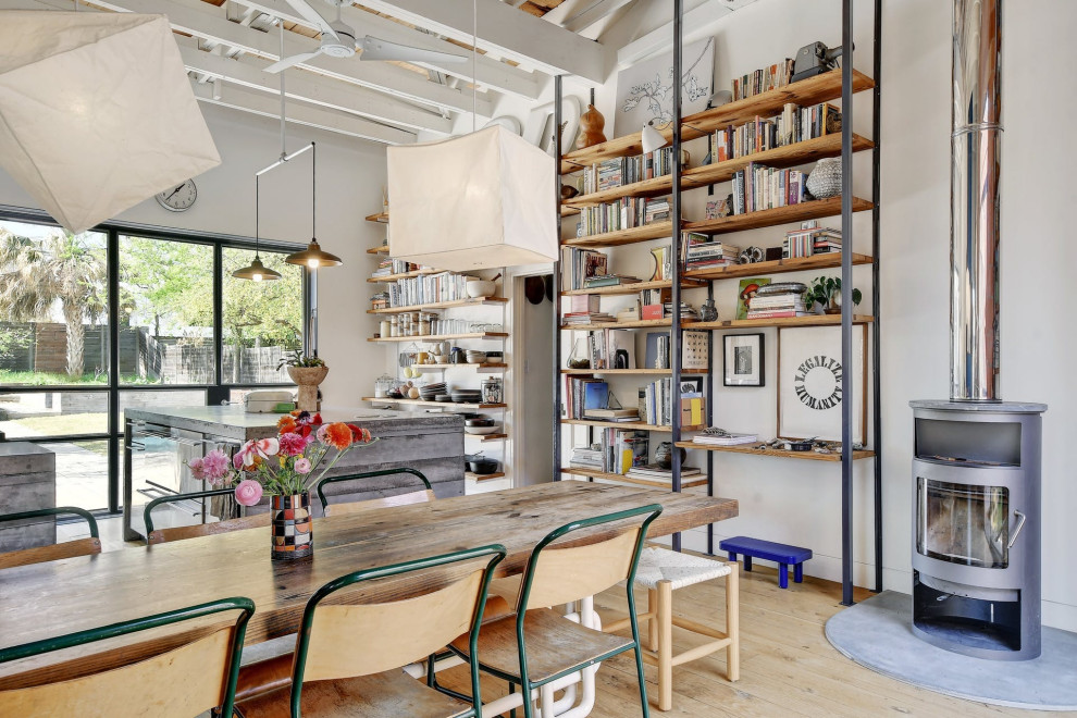 Ispirazione per una sala da pranzo aperta verso il soggiorno industriale con pareti bianche, parquet chiaro, pavimento beige e travi a vista