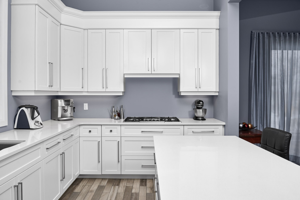 Example of a transitional l-shaped ceramic tile and gray floor enclosed kitchen design in Toronto with an undermount sink, shaker cabinets, white cabinets, quartzite countertops, stainless steel appliances, an island and white countertops