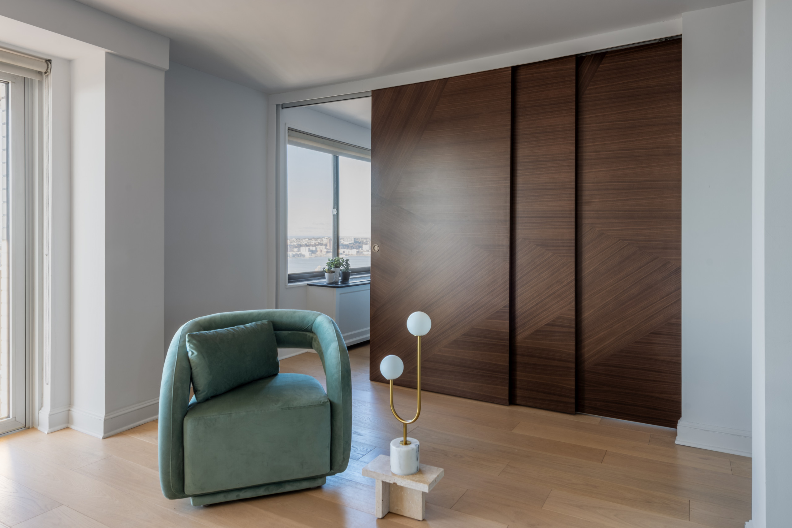 This space exudes modern elegance with a focus on clean lines and luxurious materials. The room features a stunning Italian made sliding door made of rich wood with a geometric pattern, creating a bol