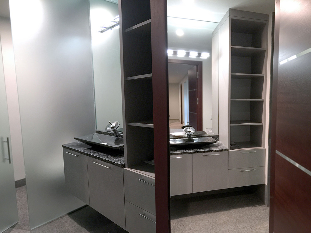 This is an example of a mid-sized modern wet room bathroom in Chicago with flat-panel cabinets, grey cabinets, a wall-mount toilet, mirror tile, white walls, porcelain floors, with a sauna, a vessel sink, engineered quartz benchtops, grey floor and a hinged shower door.