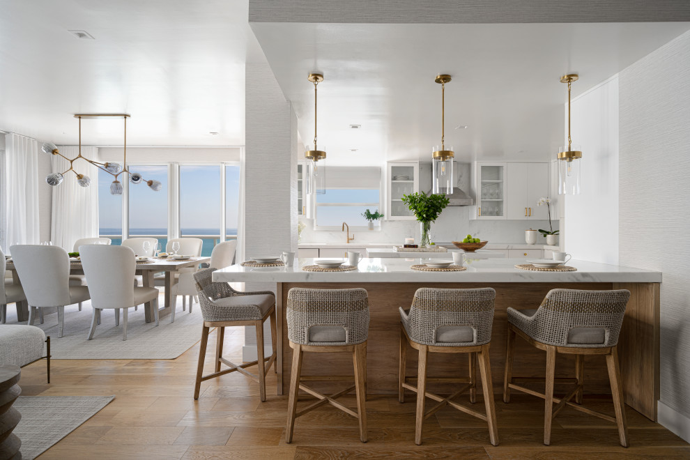 Large beach style u-shaped vinyl floor and brown floor eat-in kitchen photo in Miami with a drop-in sink, flat-panel cabinets, white cabinets, marble countertops, white backsplash, marble backsplash, stainless steel appliances, two islands and white countertops
