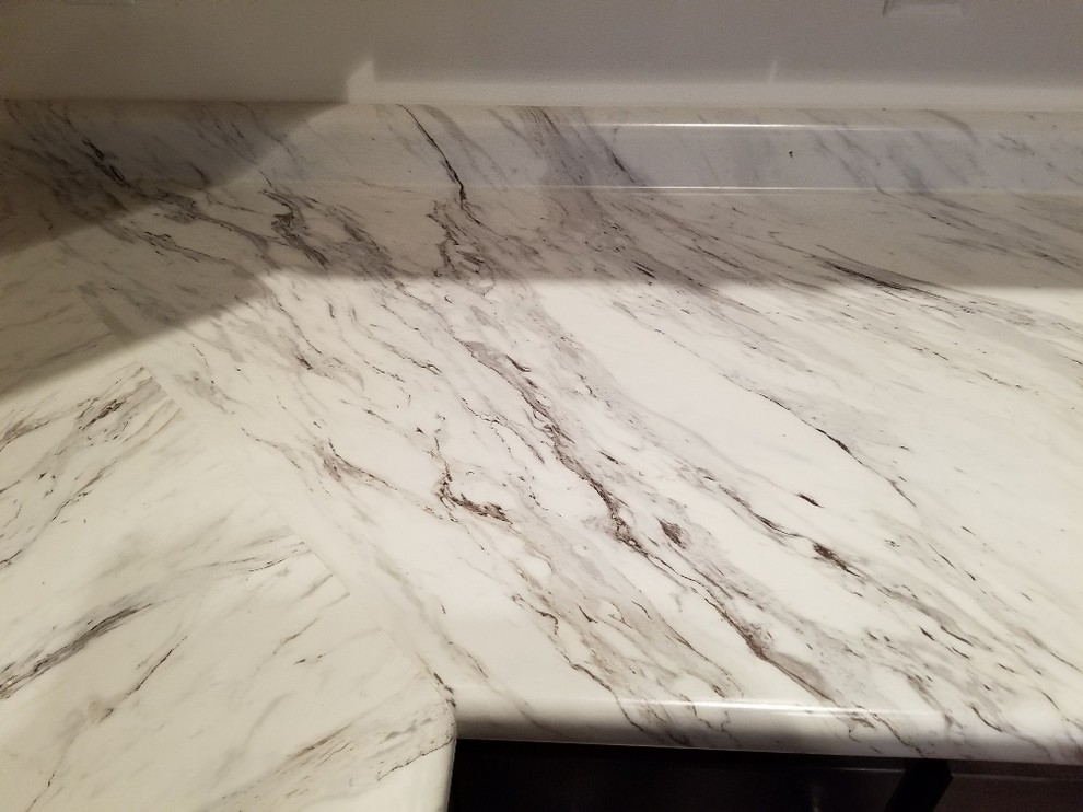 Small transitional l-shaped medium tone wood floor and brown floor kitchen photo with recessed-panel cabinets, dark wood cabinets, laminate countertops, white backsplash, no island and white countertops