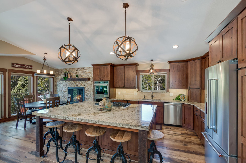 Example of a large mountain style l-shaped medium tone wood floor and brown floor enclosed kitchen design in Denver with an undermount sink, shaker cabinets, medium tone wood cabinets, granite countertops, beige backsplash, stone tile backsplash, stainless steel appliances and an island