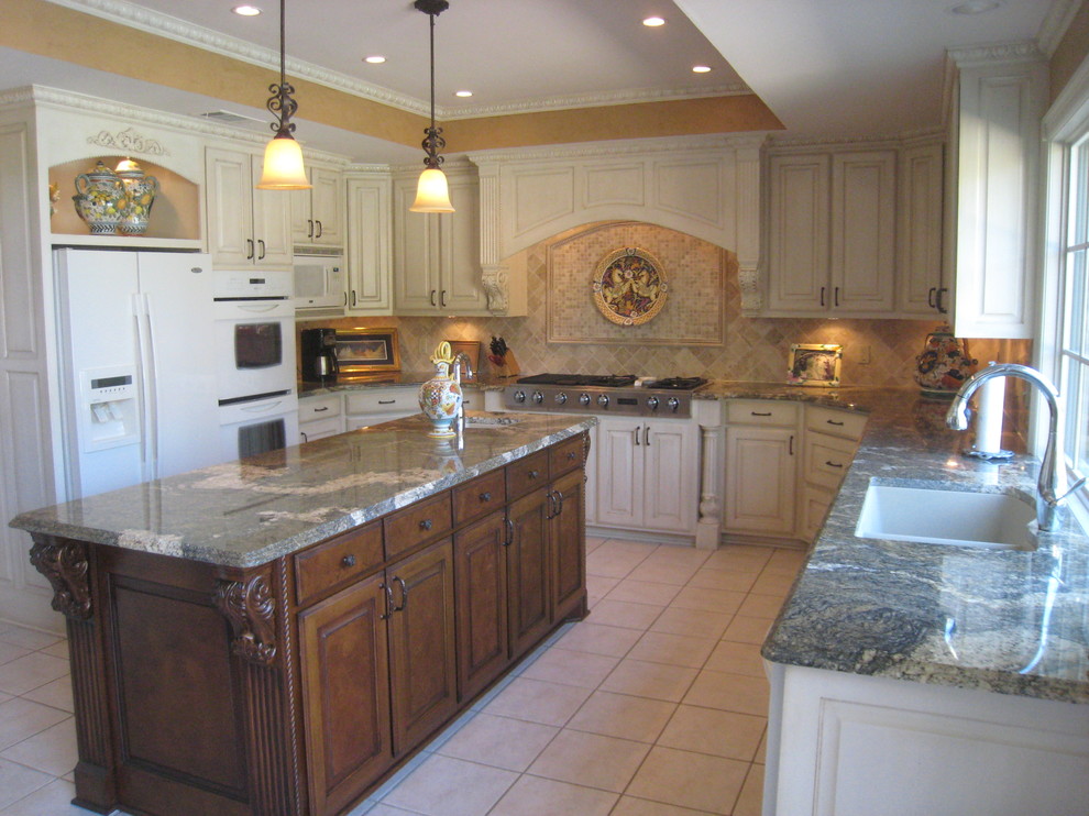 This is an example of a large traditional u-shaped eat-in kitchen in Dallas with a double-bowl sink, raised-panel cabinets, white cabinets, limestone benchtops, beige splashback, ceramic splashback, white appliances, ceramic floors, with island and beige floor.