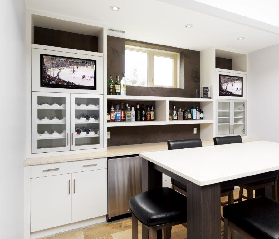 Photo of a mid-sized contemporary single-wall seated home bar in Calgary with no sink, flat-panel cabinets, white cabinets, quartzite benchtops, brown splashback and travertine floors.