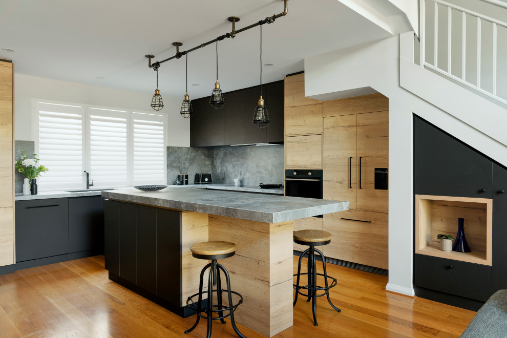 Inspiration for a mid-sized contemporary l-shaped eat-in kitchen in Perth with a drop-in sink, solid surface benchtops, grey splashback, porcelain splashback, black appliances, medium hardwood floors, with island and grey benchtop.