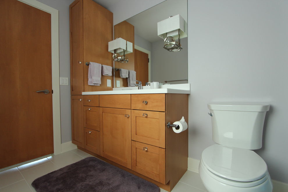 Photo of a mid-sized transitional kids bathroom in Other with shaker cabinets, medium wood cabinets, an alcove tub, an alcove shower, a two-piece toilet, white tile, porcelain tile, purple walls, porcelain floors, an undermount sink and engineered quartz benchtops.