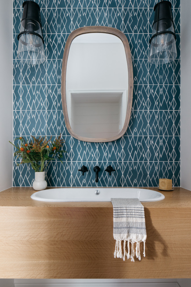 Inspiration pour un WC et toilettes rustique en bois clair de taille moyenne avec un placard à porte plane, un carrelage bleu, des carreaux de béton, un plan de toilette en bois, un plan de toilette marron, meuble-lavabo suspendu, un mur gris et un lavabo posé.