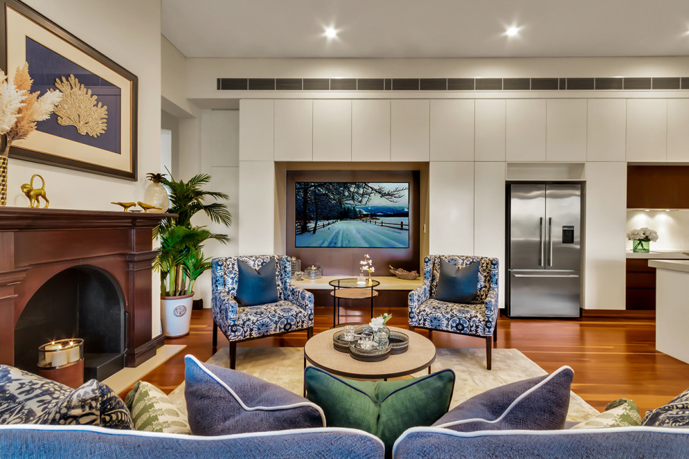 This is an example of a mid-sized traditional open concept living room in Brisbane with white walls, a standard fireplace, a wood fireplace surround, a wall-mounted tv and brown floor.
