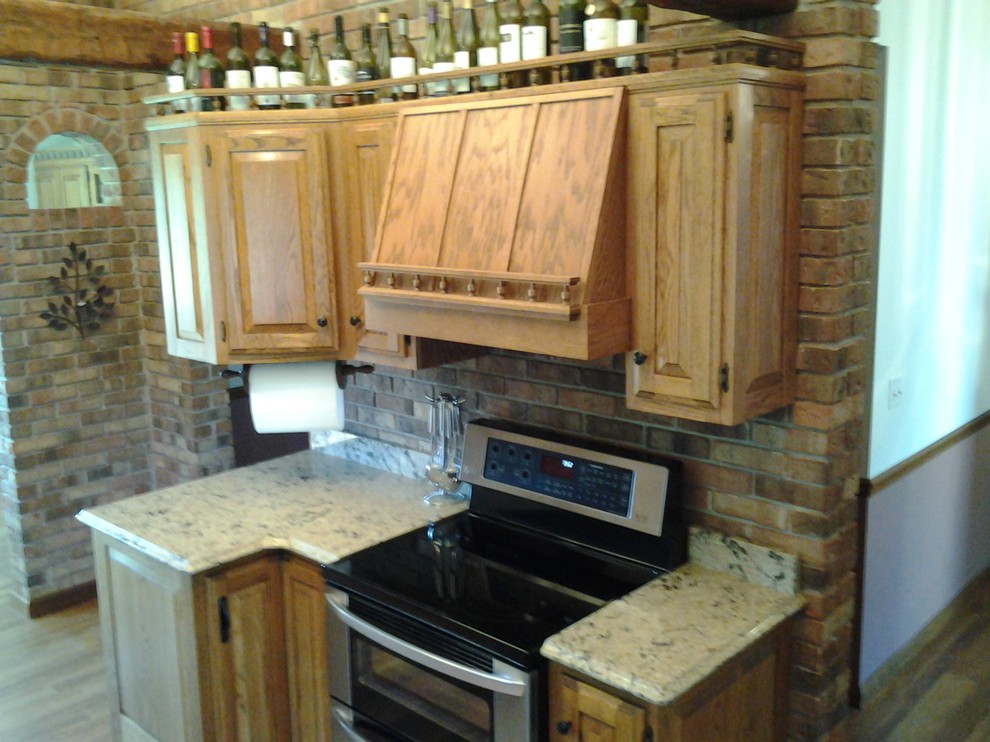 Example of a mid-sized mountain style medium tone wood floor enclosed kitchen design in Indianapolis with an undermount sink, raised-panel cabinets, medium tone wood cabinets, quartzite countertops, stainless steel appliances and no island