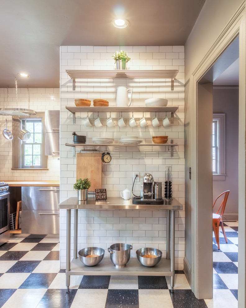 Photo of a small modern l-shaped eat-in kitchen in Other with flat-panel cabinets, stainless steel cabinets, wood benchtops, white splashback, subway tile splashback and stainless steel appliances.