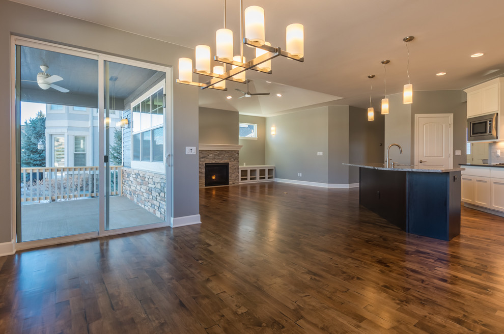 Transitional l-shaped medium tone wood floor open concept kitchen photo in Denver with an undermount sink, recessed-panel cabinets, dark wood cabinets, granite countertops, beige backsplash, stone tile backsplash, stainless steel appliances and an island