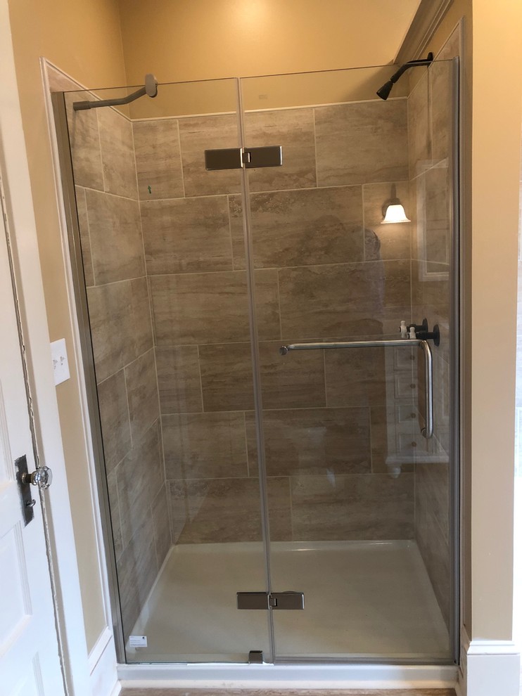 This is an example of a mid-sized modern master bathroom in New York with furniture-like cabinets, beige cabinets, an alcove tub, an alcove shower, a two-piece toilet, beige tile, cement tile, brown walls, vinyl floors, an undermount sink, engineered quartz benchtops, brown floor, a hinged shower door and beige benchtops.