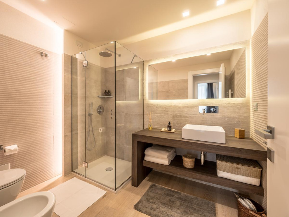 Photo of a mid-sized contemporary 3/4 bathroom in Other with open cabinets, brown cabinets, a corner shower, a wall-mount toilet, porcelain tile, beige walls, light hardwood floors, a vessel sink, wood benchtops, a hinged shower door, brown benchtops, a single vanity and a freestanding vanity.