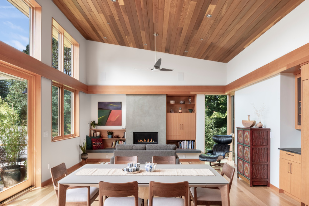 This is an example of a contemporary dining room in Portland with white walls, light hardwood floors, a standard fireplace, beige floor, vaulted and wood.