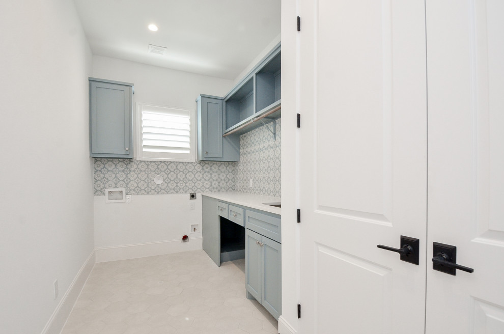 Photo of a large transitional single-wall dedicated laundry room in Houston with an undermount sink, shaker cabinets, turquoise cabinets, quartz benchtops, multi-coloured splashback, porcelain splashback, white walls, porcelain floors, a side-by-side washer and dryer, beige floor and white benchtop.