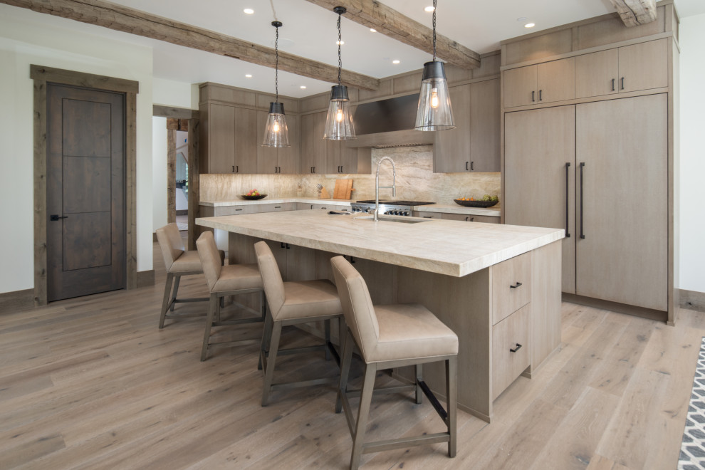 Design ideas for an expansive country l-shaped open plan kitchen with a drop-in sink, flat-panel cabinets, light wood cabinets, quartzite benchtops, beige splashback, stone slab splashback, stainless steel appliances, light hardwood floors, with island, brown floor and beige benchtop.