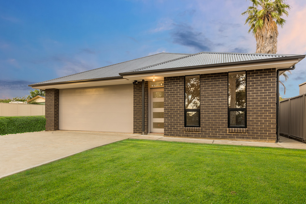 Photo of a mid-sized modern one-storey brick black house exterior in Adelaide with a hip roof and a metal roof.