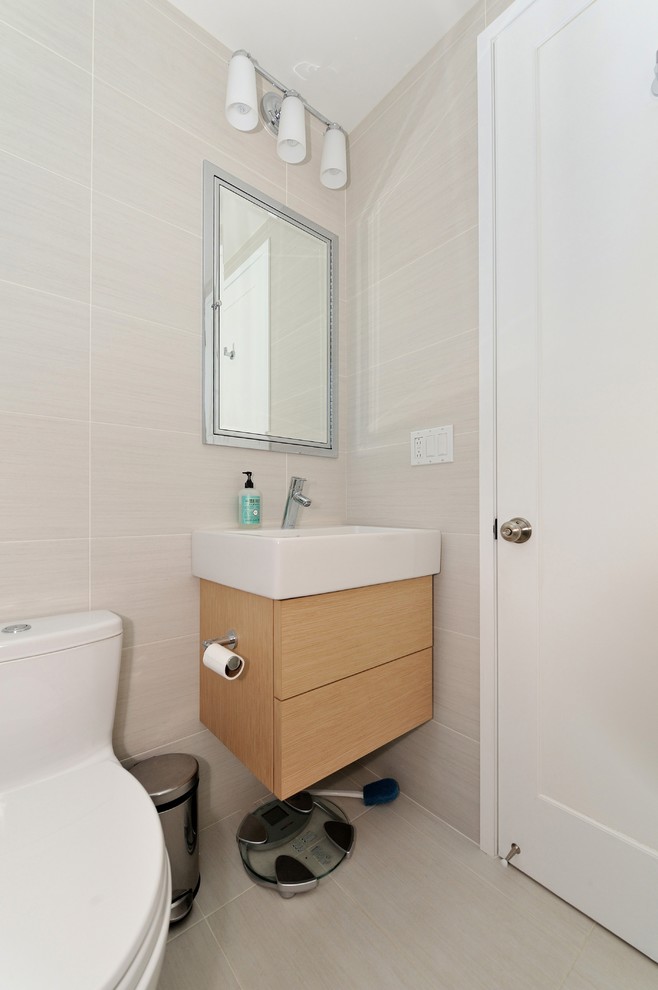 Mid-sized contemporary bathroom in New York with an integrated sink, flat-panel cabinets, light wood cabinets, solid surface benchtops, a corner shower, a one-piece toilet, white tile, ceramic tile, beige walls and ceramic floors.