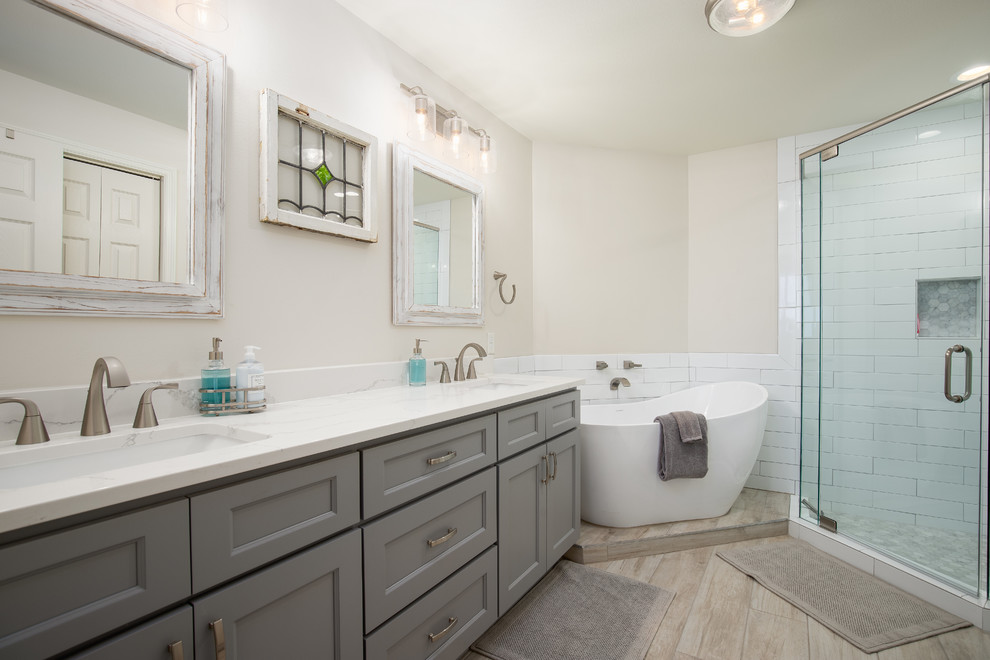 Design ideas for a transitional master bathroom in Miami with grey cabinets, a freestanding tub, a corner shower, white tile, subway tile, beige walls, an undermount sink, beige floor, a hinged shower door, white benchtops and recessed-panel cabinets.
