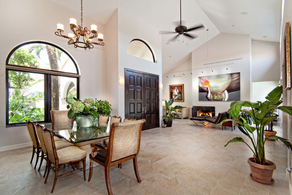 Inspiration for a large tropical open plan dining in Miami with white walls, travertine floors, a standard fireplace and a stone fireplace surround.