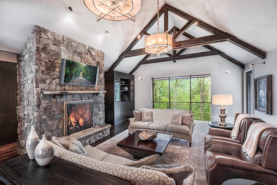 Photo of a large transitional open concept living room in Other with grey walls, dark hardwood floors, a standard fireplace, a stone fireplace surround, a wall-mounted tv and brown floor.