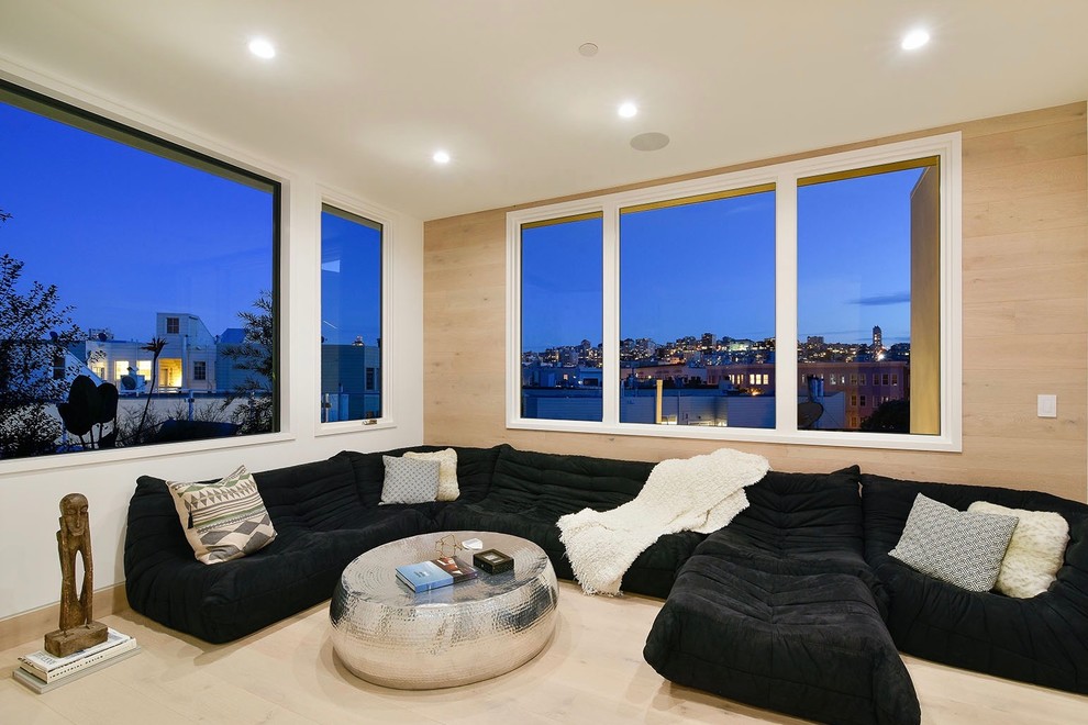 This is an example of a large contemporary enclosed family room in San Francisco with white walls, light hardwood floors, no fireplace and no tv.