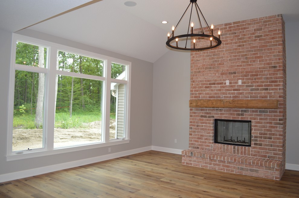 This is an example of a mid-sized traditional open concept living room in Other with beige walls, medium hardwood floors, a standard fireplace, a brick fireplace surround, a freestanding tv and orange floor.