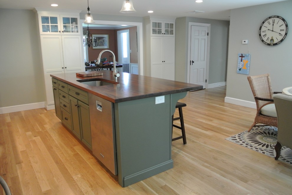 Example of a transitional galley light wood floor eat-in kitchen design in Boston with an undermount sink, wood countertops, stainless steel appliances, an island, shaker cabinets, white cabinets, white backsplash, ceramic backsplash and brown countertops