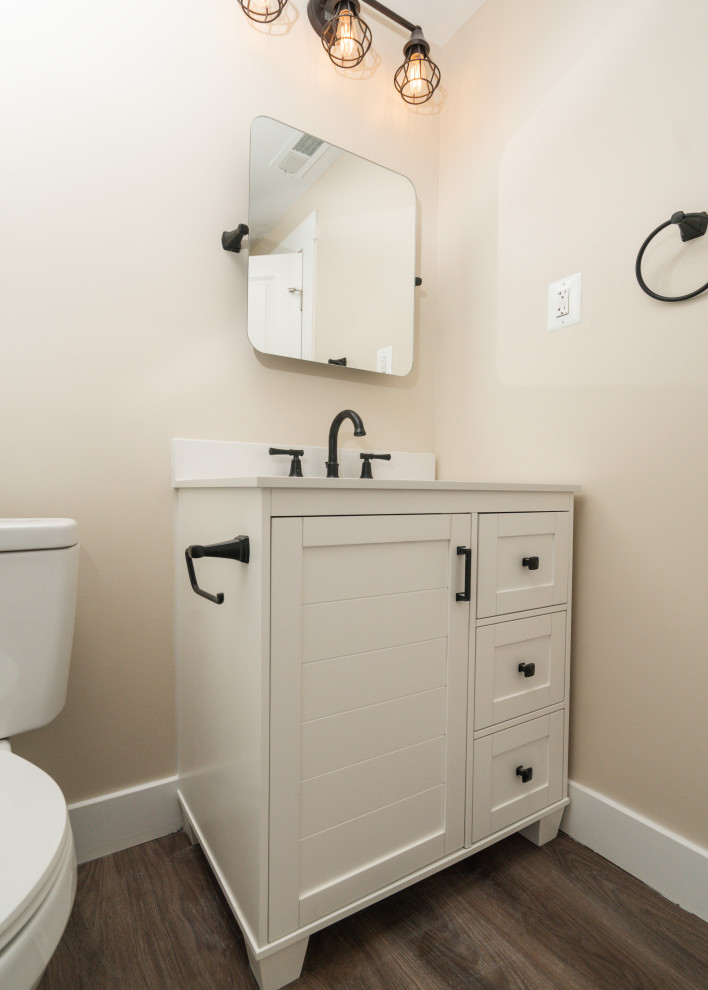 Cette photo montre un petit WC et toilettes chic avec un placard à porte shaker, des portes de placard blanches, WC séparés, un carrelage blanc, un mur beige, un sol en vinyl, un lavabo intégré, un plan de toilette en marbre, un sol marron, un plan de toilette blanc et meuble-lavabo sur pied.
