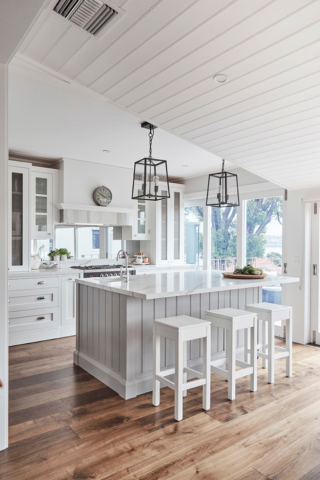 Inspiration for a mid-sized country u-shaped kitchen pantry in Sydney with a farmhouse sink, shaker cabinets, white cabinets, marble benchtops, white splashback, subway tile splashback, stainless steel appliances, light hardwood floors and with island.