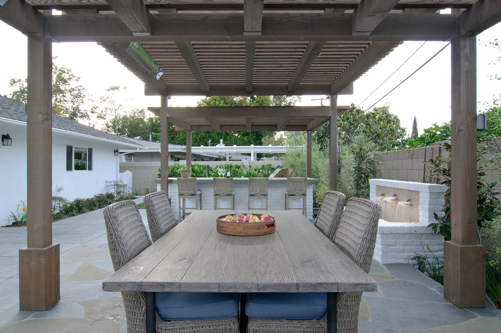 Design ideas for a large transitional backyard patio in Orange County with an outdoor kitchen, natural stone pavers and a pergola.