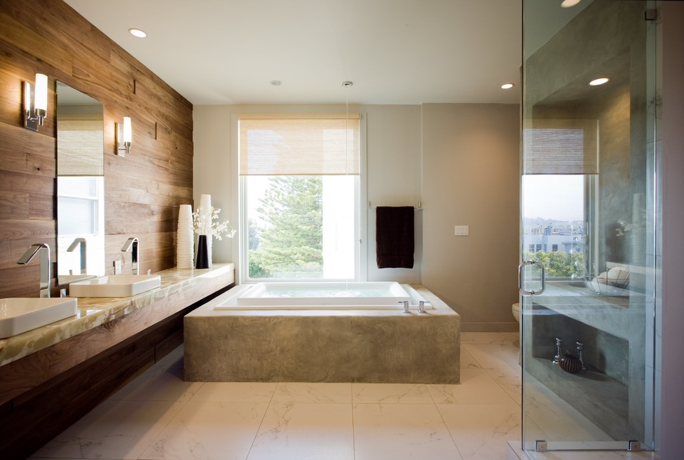 Inspiration for a large contemporary master bathroom in San Francisco with a vessel sink, onyx benchtops, a freestanding tub, a corner shower, a one-piece toilet, white tile, ceramic tile, white walls and porcelain floors.