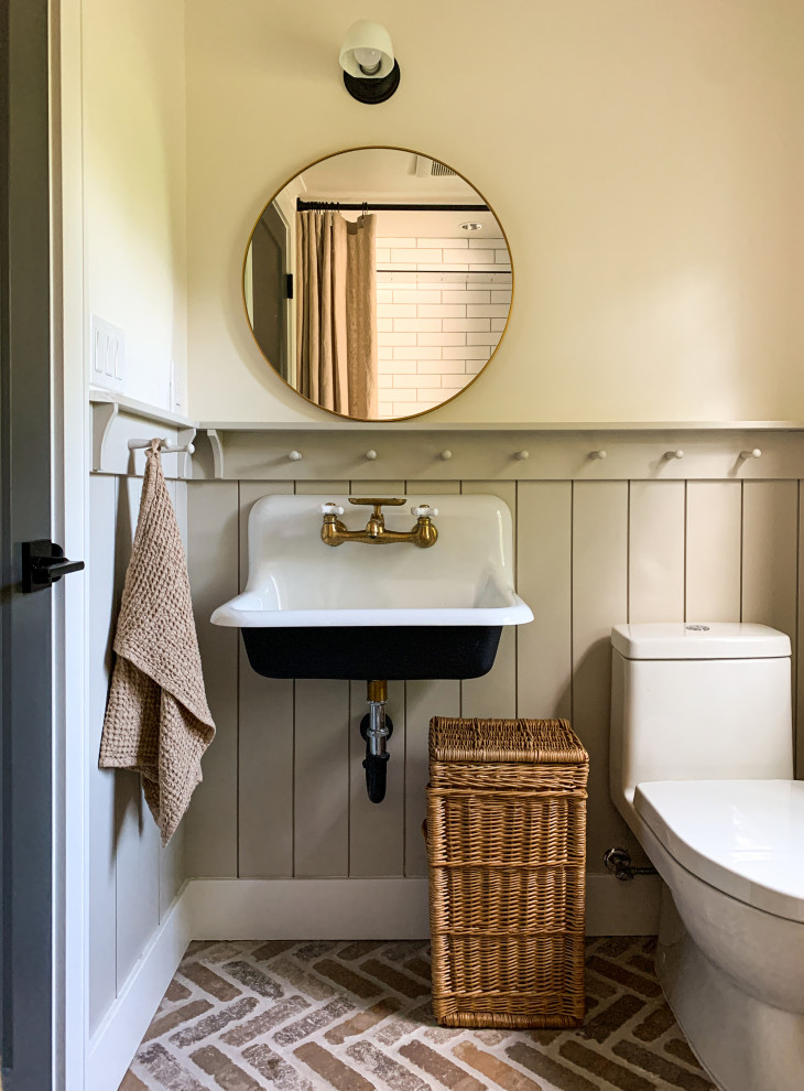 Inredning av ett lantligt litet en-suite badrum, med svarta skåp, en toalettstol med hel cisternkåpa, vit kakel, keramikplattor, vita väggar, tegelgolv, ett väggmonterat handfat och dusch med duschdraperi