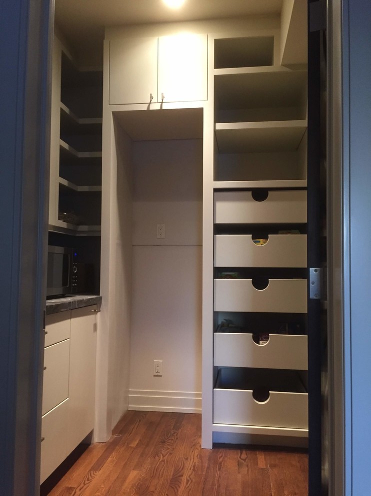 This is an example of a mid-sized transitional gender-neutral walk-in wardrobe in Calgary with flat-panel cabinets, white cabinets, medium hardwood floors and brown floor.
