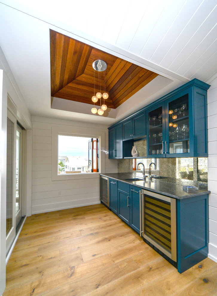 Photo of a mid-sized beach style single-wall wet bar in Philadelphia with an undermount sink, shaker cabinets, blue cabinets, granite benchtops, mirror splashback and medium hardwood floors.
