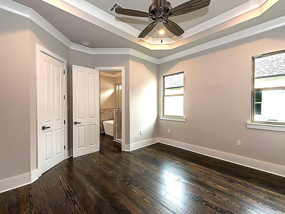 Mid-sized traditional guest bedroom in New Orleans with beige walls, dark hardwood floors and brown floor.
