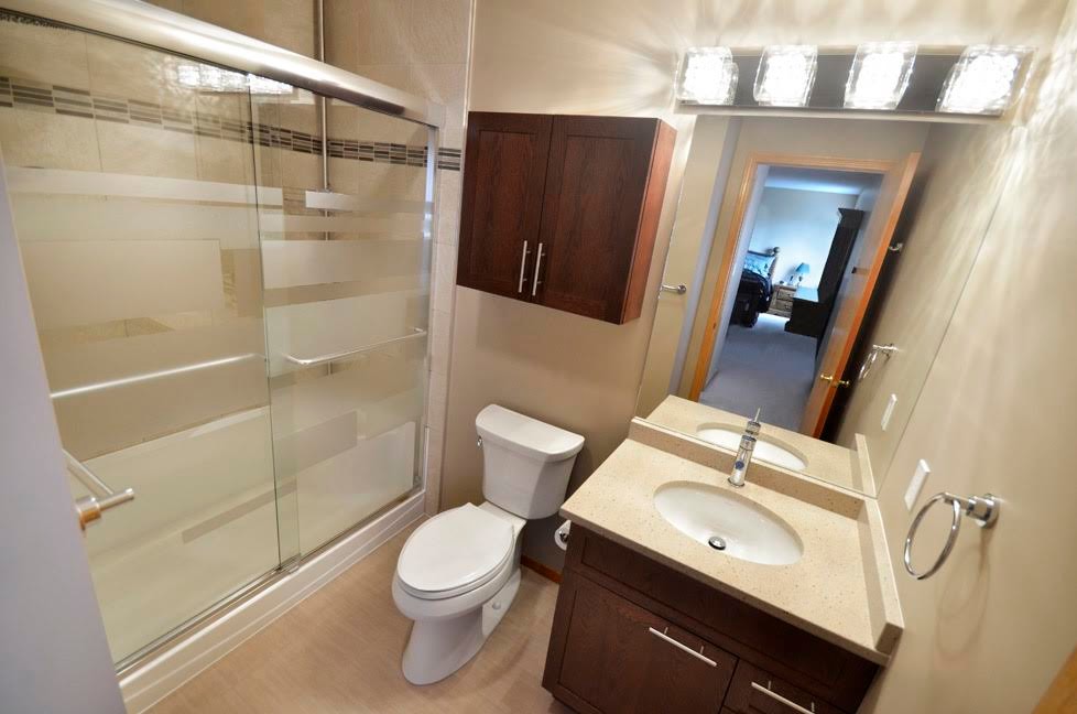 Small contemporary 3/4 bathroom in Other with shaker cabinets, medium wood cabinets, an alcove shower, beige walls, an undermount sink, a one-piece toilet, stone tile, vinyl floors, engineered quartz benchtops and beige tile.