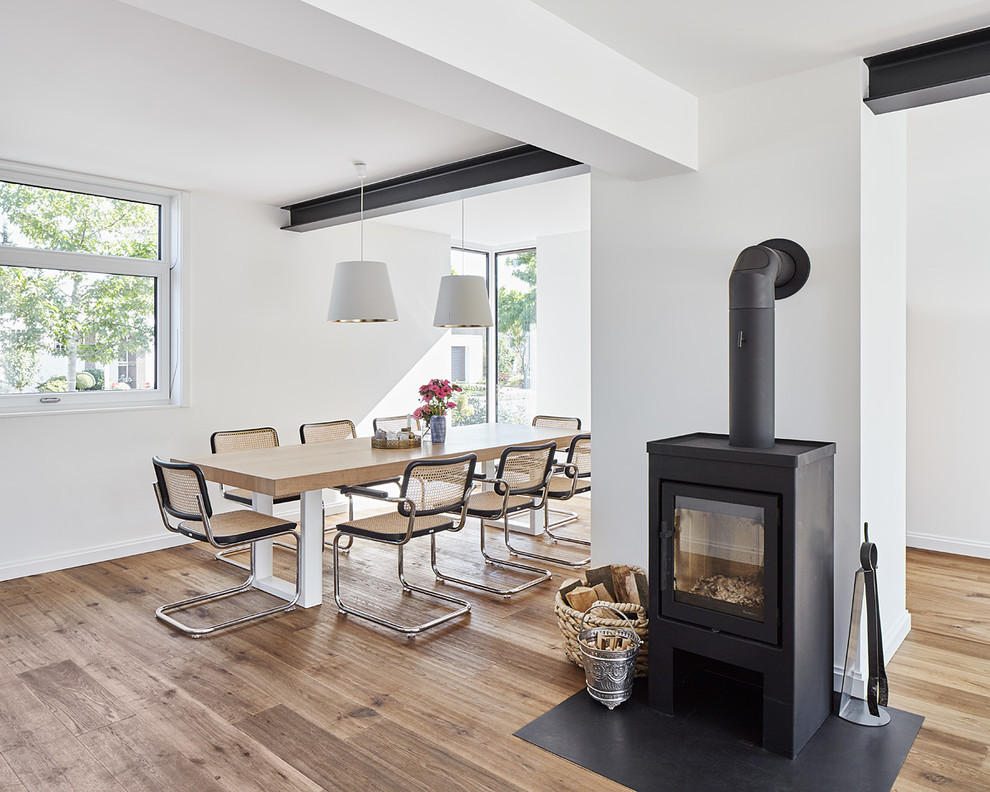 Inspiration for a mid-sized scandinavian open plan dining in Dusseldorf with white walls, light hardwood floors and a wood stove.