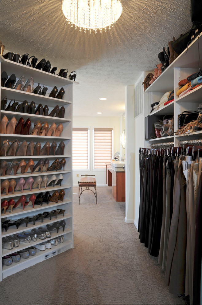 Photo of a large traditional gender-neutral walk-in wardrobe in Other with white cabinets and carpet.