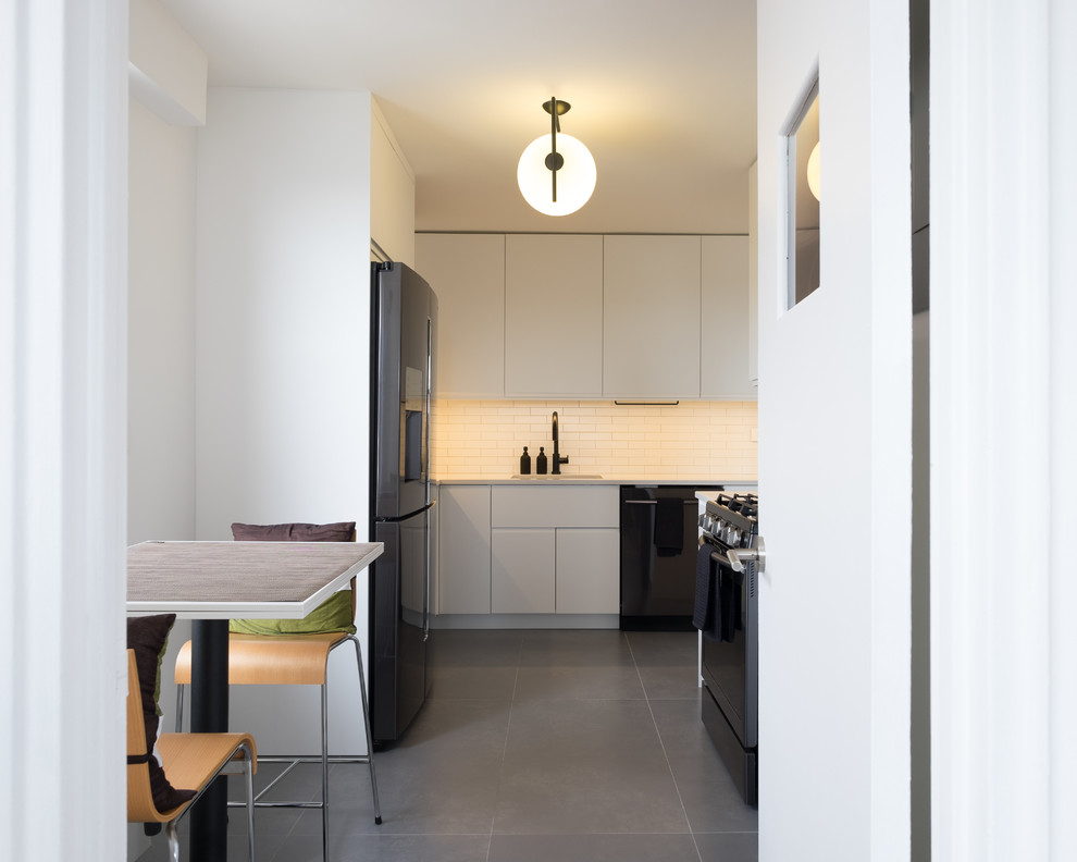 Design ideas for a small contemporary u-shaped separate kitchen in New York with an undermount sink, flat-panel cabinets, white cabinets, quartz benchtops, white splashback, subway tile splashback, black appliances, concrete floors, no island and grey floor.