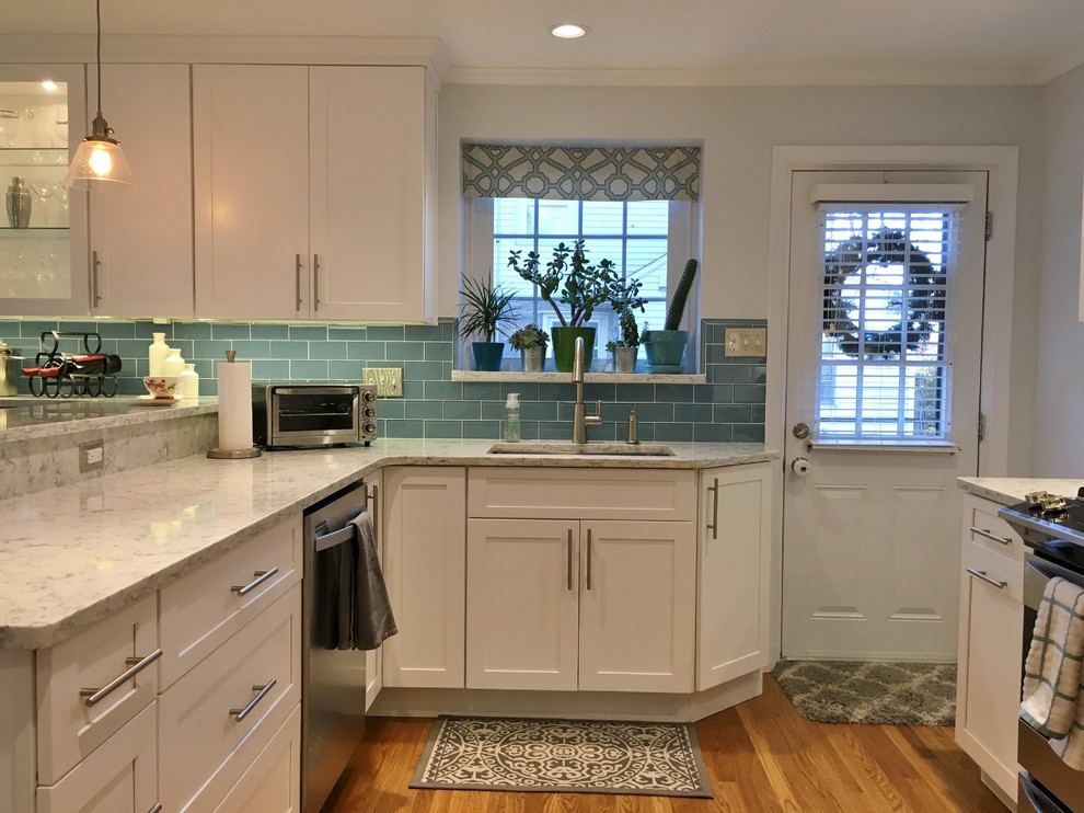 Small transitional l-shaped eat-in kitchen in Philadelphia with an undermount sink, shaker cabinets, white cabinets, quartz benchtops, blue splashback, stainless steel appliances, medium hardwood floors and brown floor.