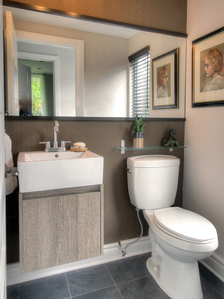 This is an example of a small contemporary powder room in Montreal with a wall-mount sink, flat-panel cabinets, a two-piece toilet, gray tile, stone tile, brown walls, slate floors and light wood cabinets.