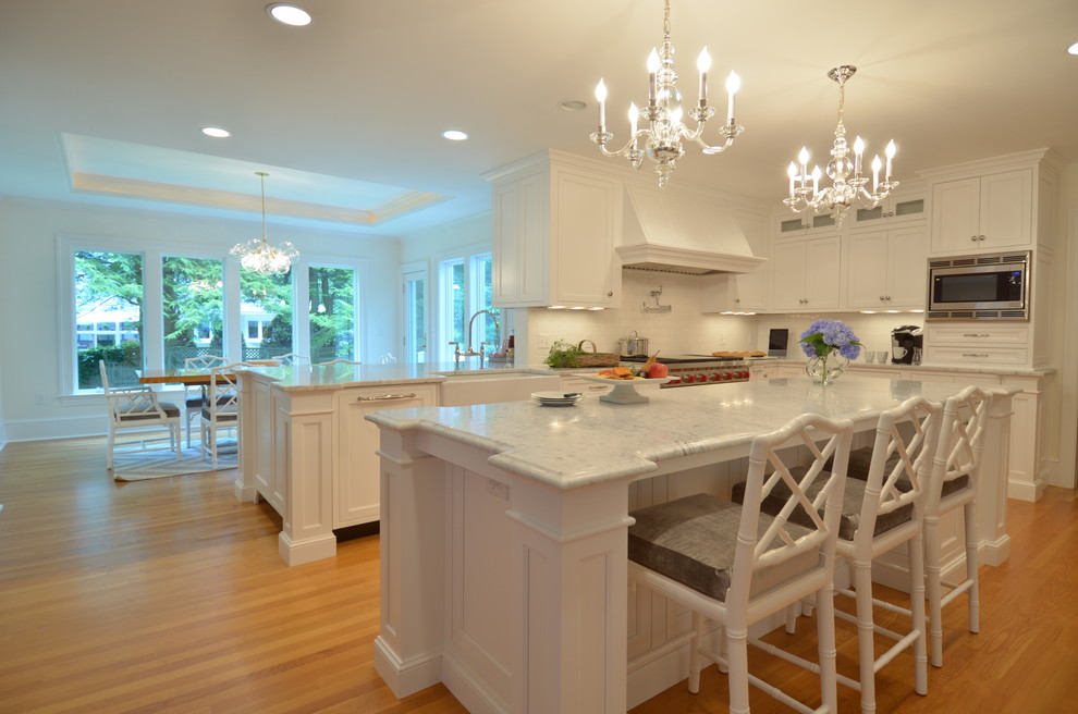 Eat-in kitchen - transitional u-shaped medium tone wood floor eat-in kitchen idea in Boston with a farmhouse sink, beaded inset cabinets, white cabinets, marble countertops, white backsplash, subway tile backsplash, stainless steel appliances and an island