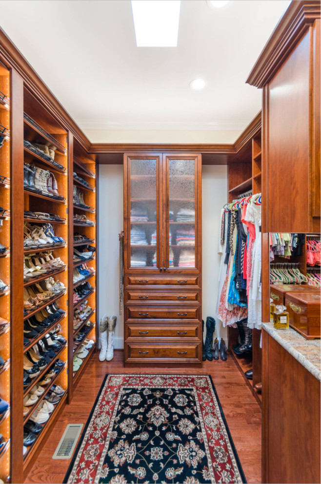 Large traditional gender-neutral walk-in wardrobe in Richmond with raised-panel cabinets, medium wood cabinets and brown floor.